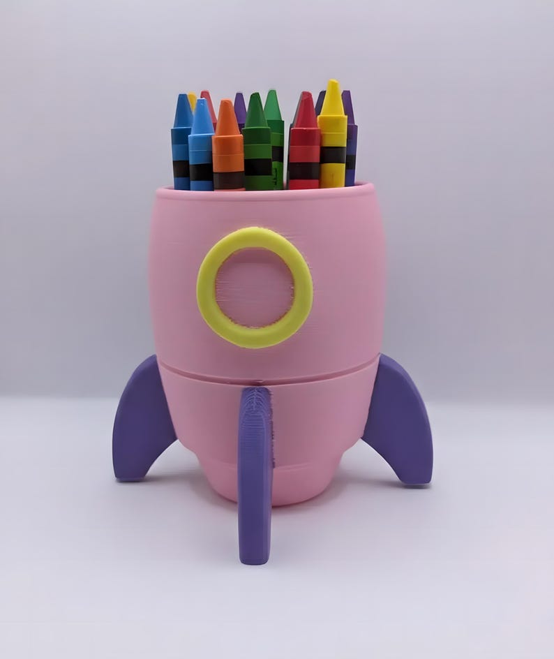 Pink, yellow, and purple 3D-printed rocket crayon holder filled with crayons